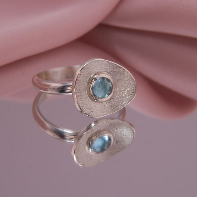 Frontansicht auf den Designerring Isola aus 925 Silber mit rundem Blautopas Swiss Blue und diamantierter Vertiefung.